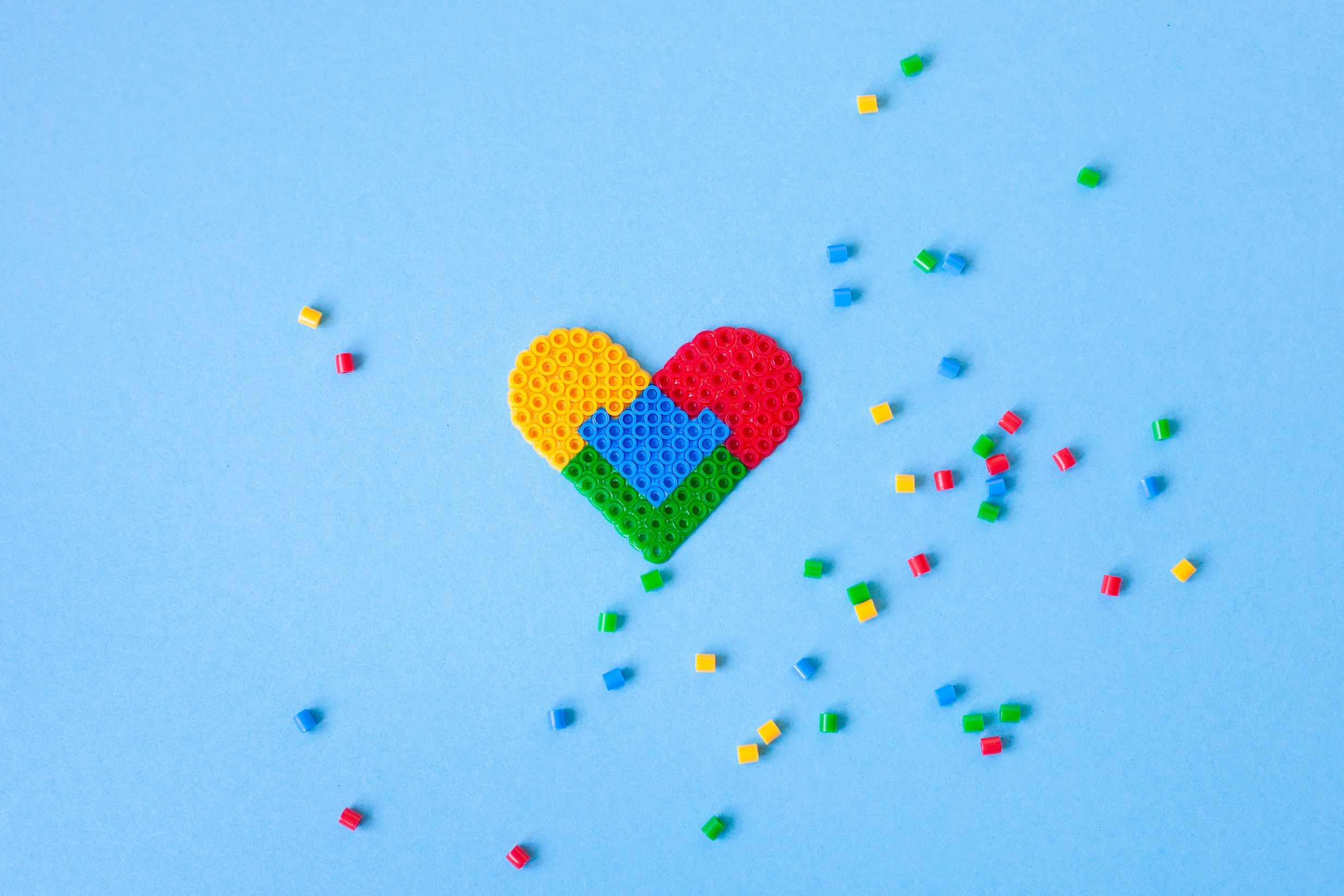 Colorful mosaic heart and  scattered pieces on a blue background.